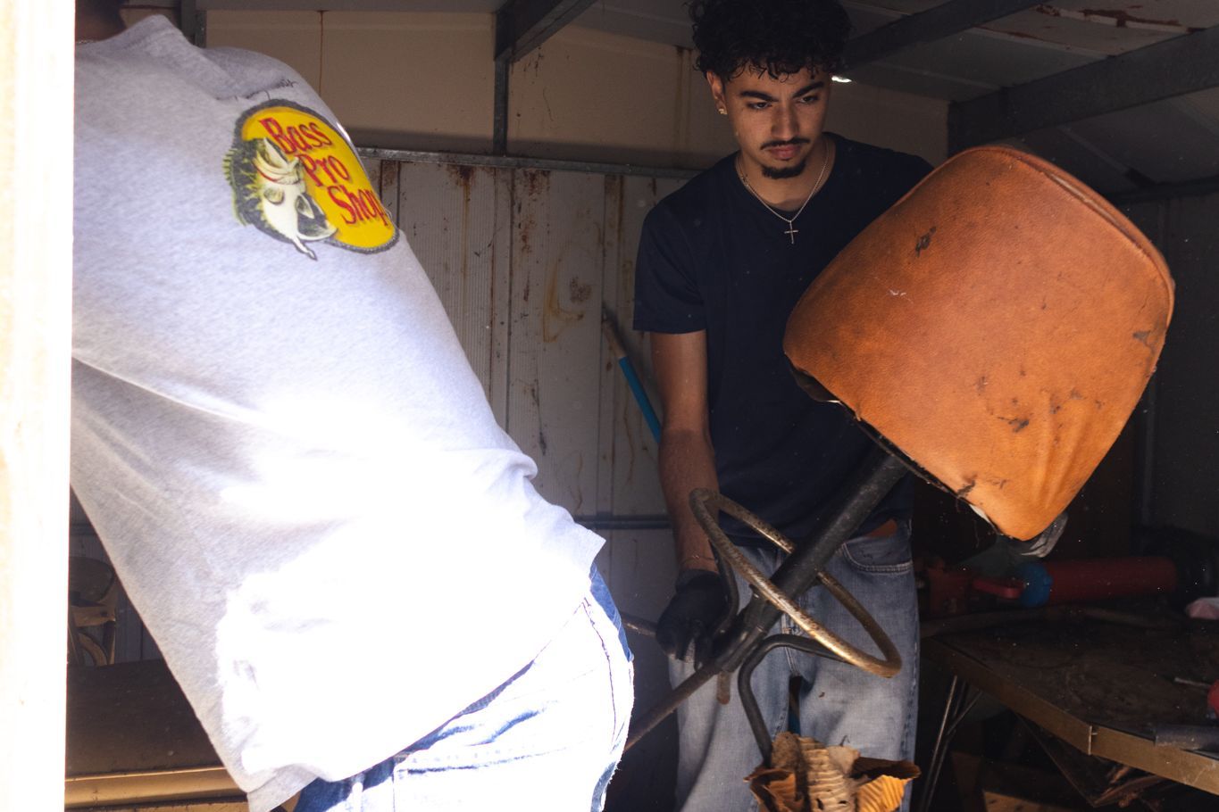Crew member carrying an old chair out of the shed